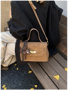 Close-up of vintage brown suede crossbody bag with gold clasp and horse charm accessory
