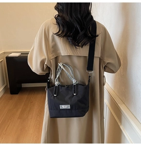 Sac fourre-tout noir en nylon avec poignée en corde porté par un mannequin en trench