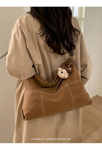 Detail of retro brown tote bag with white contrast stitching and plush bear charm