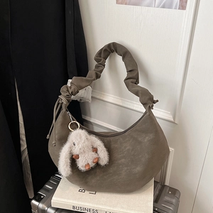 Detail of dark faux leather crescent bag with cloud-pleated strap and bunny charm