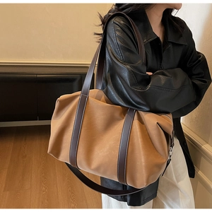 Detailed view of camel tote bag with dark brown handles shown on a model's shoulder