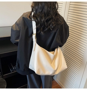Detail of minimalist cream leather hobo bag with a gold metal buckle on shoulder strap