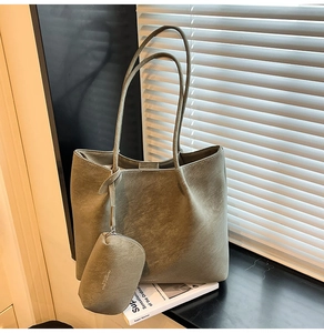 Sage green tote bag and matching pouch with textured matte finish on a white lookbook