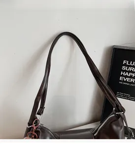 Detail of dark brown leather tote bag showing durable handles and pink chain accessory