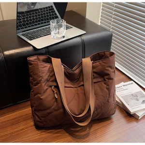 Detailed wave quilted pattern on dark brown tote bag placed on a wooden office desk