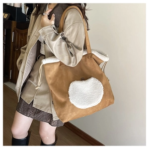 Detailed texture of brown suede tote bag featuring white faux shearling trim and straps
