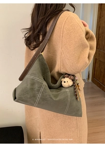 Detail of dark green tote bag with white contrast stitching and bear charm on model