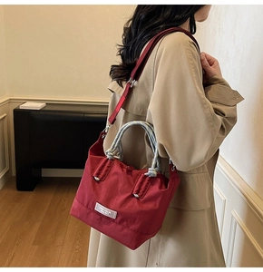Détail du sac fourre-tout en nylon rouge avec anses tissées colorées et étiquette de marque