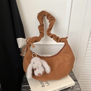 Close-up of caramel crescent bag with ruched strap and cute white bunny charm accessory