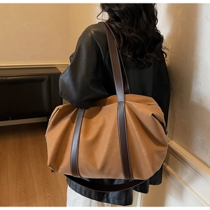 Close-up of a large tan leather tote bag featuring contrast stitching and sturdy straps