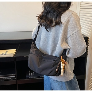 Minimalist black nylon crossbody bag side view with ethnic bead charm and large capacity