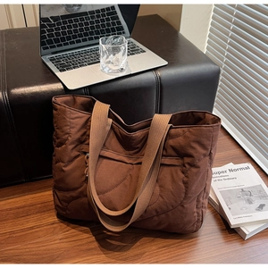 Macro shot of dark brown quilted tote bag showing high-quality wave stitching and material
