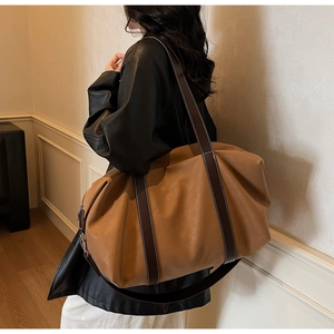 Detailed view of camel large capacity shoulder bag with contrasting brown leather handles