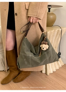 Detailed view of deep green vintage tote bag with contrast stitching and teddy bear charm