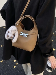 Chic tan bucket bag with plush rabbit charm and crossbody strap for autumn winter style