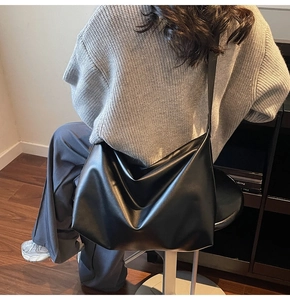 Lifestyle view of a spacious black leather tote bag worn by a model in a cozy setting