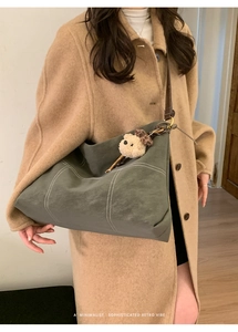 Detail of dark green matte tote bag with contrast white stitching and bear charm