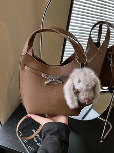Brown leather bucket bag with silver bow clasp, grey rabbit charm and shoulder strap