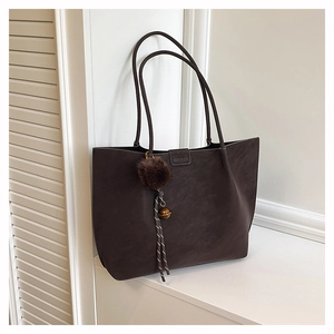 Detail of dark brown faux suede tote bag with fur ball charm and brand logo