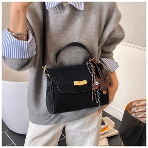 Detail view of black vintage crossbody bag with gold lock and brown horse charm