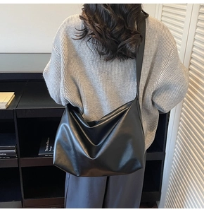 Detail of a black large-capacity minimalist hobo shoulder bag worn on a model back
