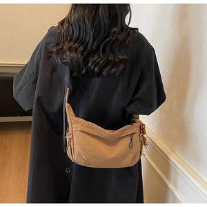 Detail of a brown nylon crescent bag with wooden beads and black shoulder strap