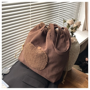 Detail of vintage brown suede tote bag with plush heart embroidery and woven drawstring