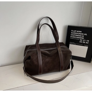 Detail view of large dark brown leather travel bag with matte finish and silver zippers