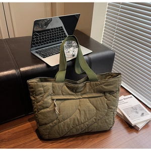 Detail of army green quilted tote bag showing wave stitching and front zipper pocket