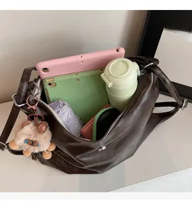 Interior detail of large brown crossbody bag showing spacious storage for tablet and umbrella