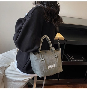 Détail du sac fourre-tout en nylon vert sauge avec poignées tissées et étiquette de marque