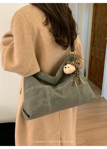 Detail of olive green tote bag with contrast stitching and a plush bear charm