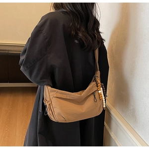 Detail of khaki nylon shoulder bag featuring decorative wooden beads and drawstring texture