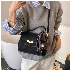 Detail of black tote bag with gold twist lock and cute dachshund charm on a model