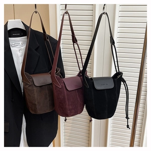 Close-up of matte suede bucket bags in coffee, burgundy and black with leather straps