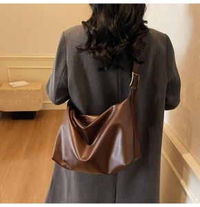 Detail of dark brown leather hobo bag showing large capacity and soft texture drape
