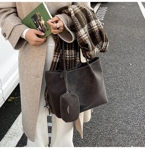 Close-up of matte leather tote bag and zip pouch on a stylish wool autumn coat