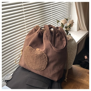 Detailed close-up of dark brown canvas tote bag with a plush heart-shaped pocket and drawstrings