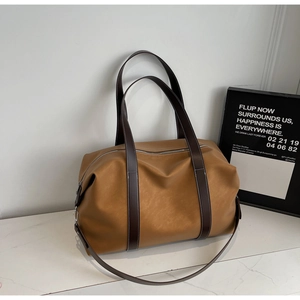 Detailed side view of a large brown leather travel tote bag on a marble surface