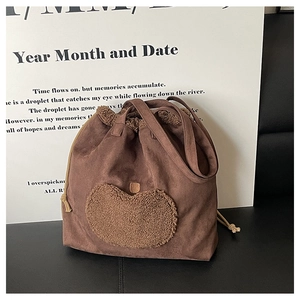 Detail of vintage brown suede tote bag with plush heart embroidery and drawstring design