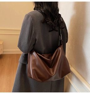 Detail of dark brown leather tote bag showing soft texture and metal buckle on strap