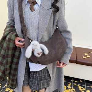 Close-up of a dark brown suede hobo bag with a white rabbit plush charm for daily style