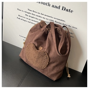 Detailed close-up of brown suede tote bag featuring a plush heart and drawstring design