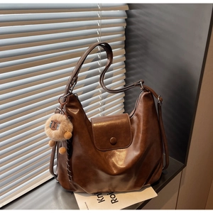 Detail view of large dark brown hobo shoulder bag with plush lion charm and glossy finish