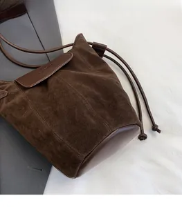 Detail of the brown suede bucket bag featuring a drawstring closure and logo embossing