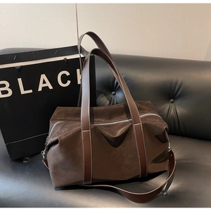 Detail of a brown suede oversized tote bag featuring durable leather straps and metal zipper