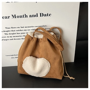 Detail of vintage brown suede tote bag featuring a white faux fur heart patch and drawstring