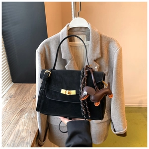 Detail of a black matte leather handbag with gold twist lock and dachshund dog charm