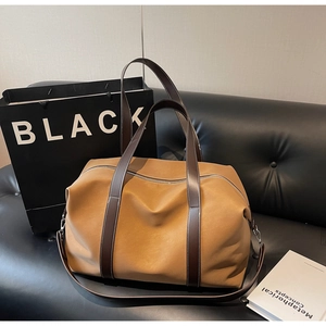 Detail view of large capacity caramel leather travel bag on sofa with shoulder strap
