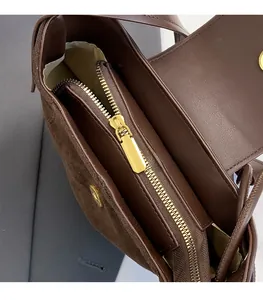 Macro detail of high-quality golden zipper and stitching on a brown suede shoulder bag
